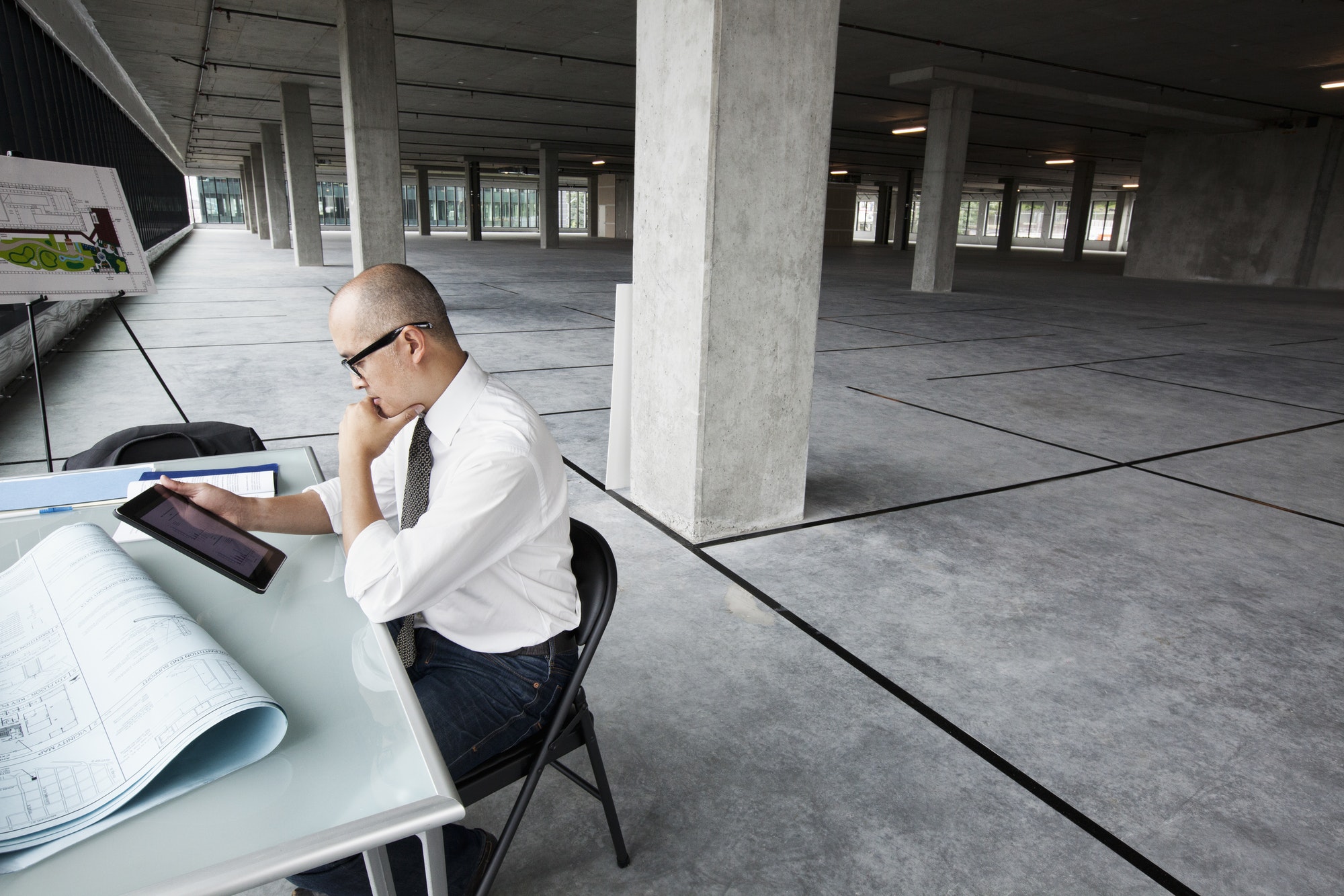 Asian architect woking on workspaces in a new raw office location.