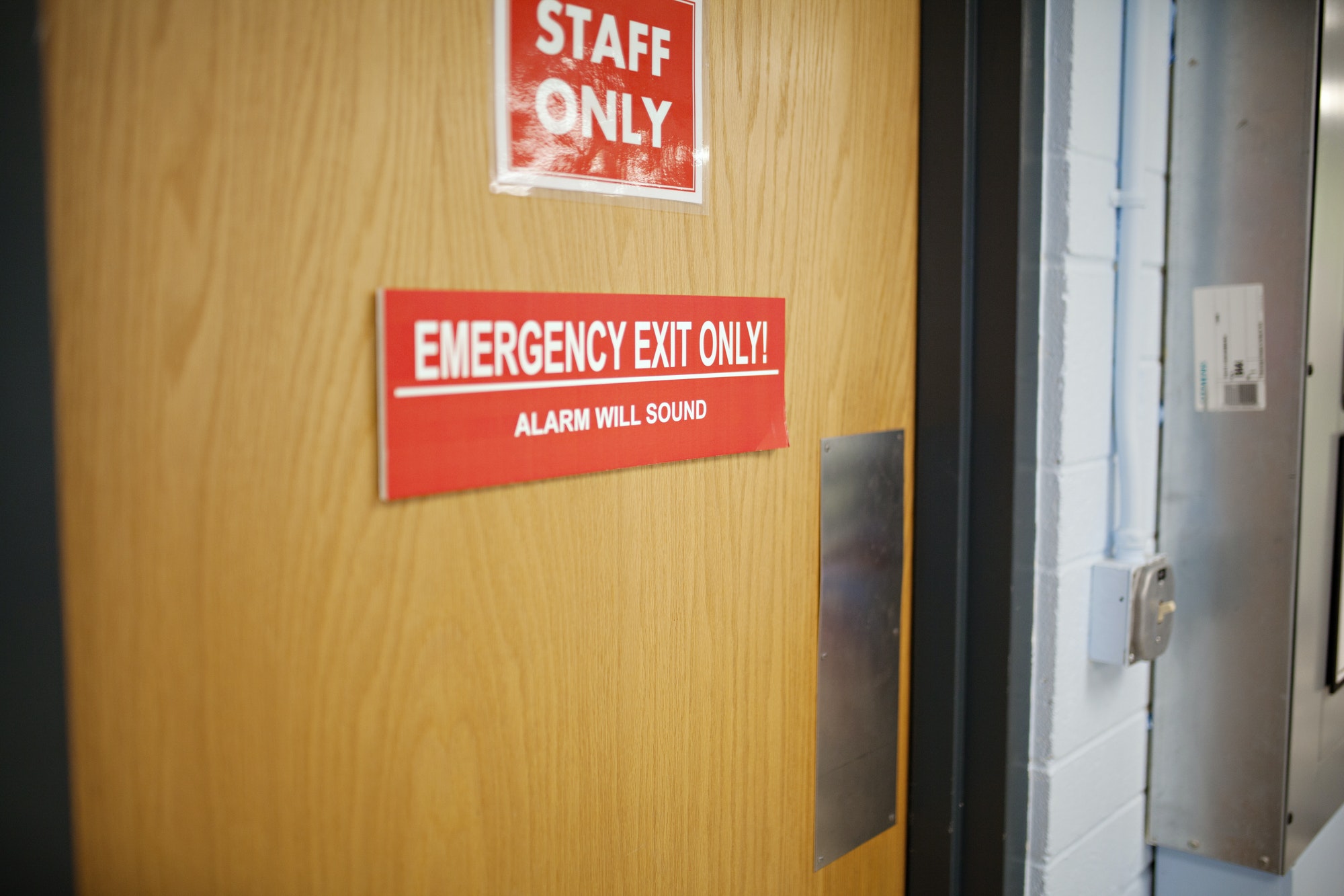 door with signs saying staff only and emergency exit alarm will sound