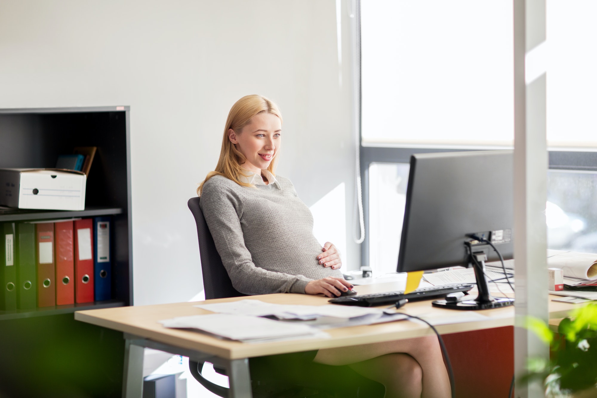 pregnant businesswoman with computer at office